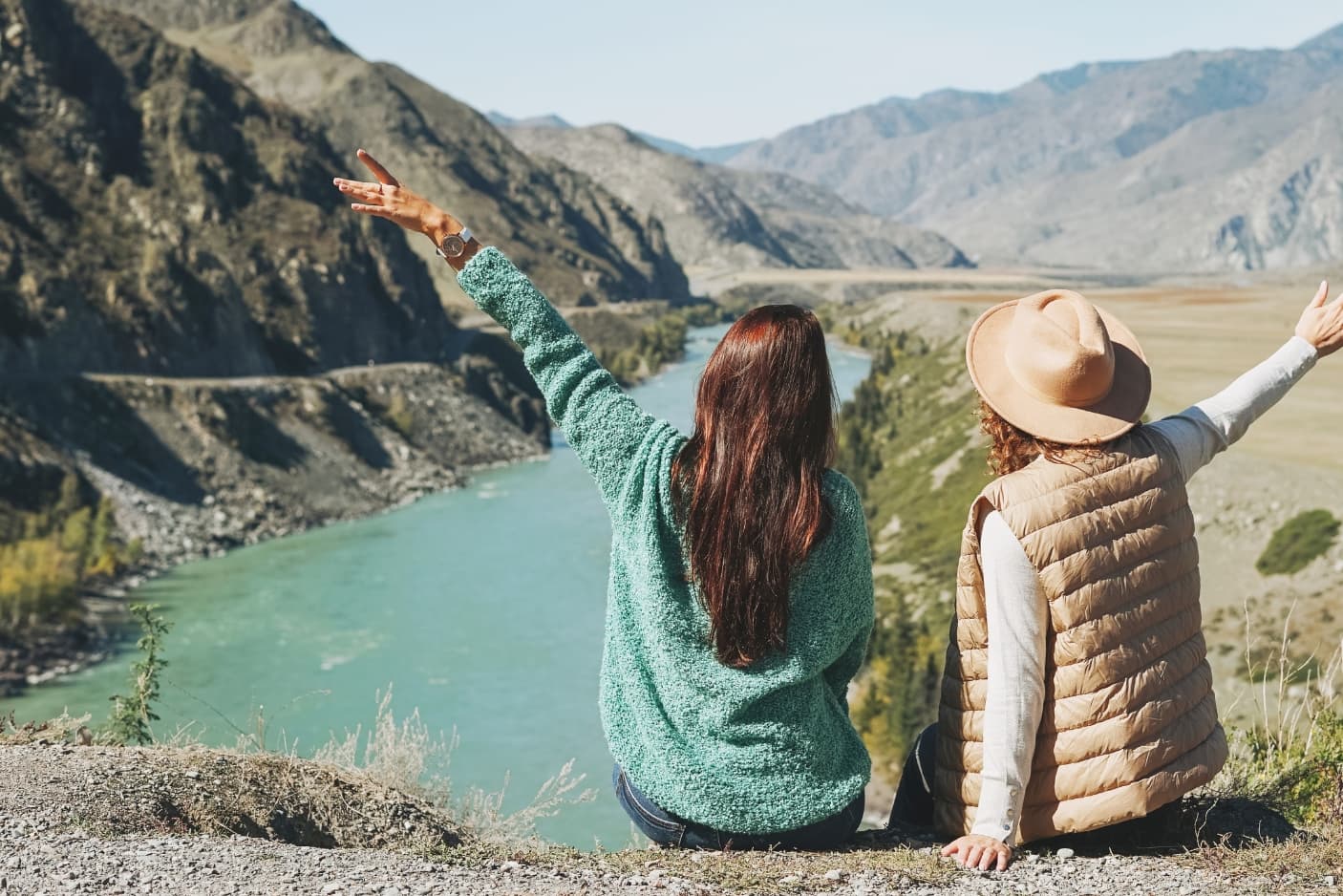 Zwei Frauen sitzen auf einer Klippe oberhalb eines Bergsees