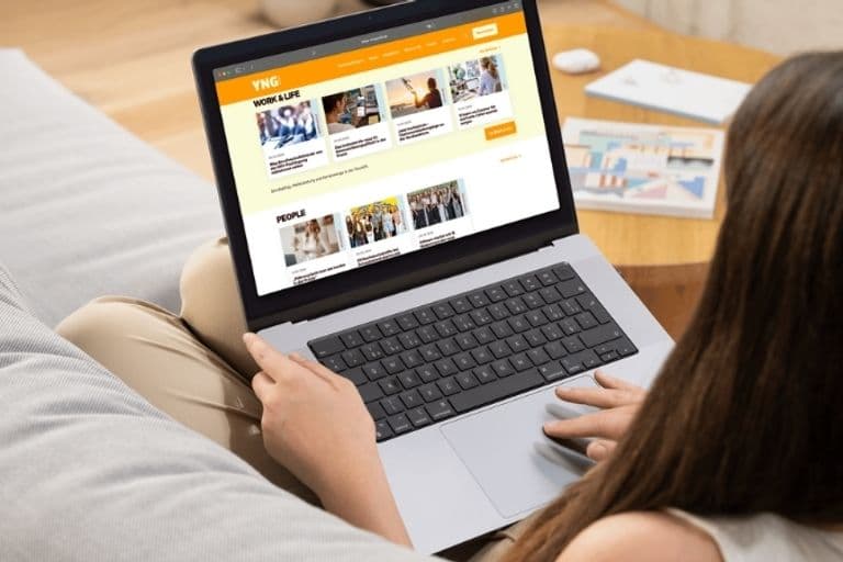 Eine Frau sitzt auf einem Sofa und liest die neue Seite der TRVL COUNTER Plattform Young Professionals