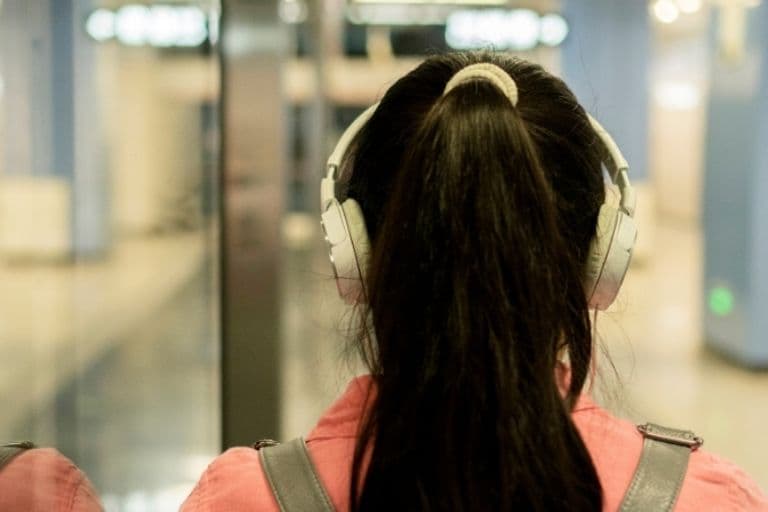 Eine junge Frau läuft mit Kopfhörern zur U-Bahn