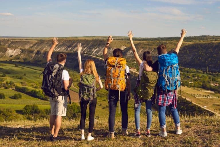 Junge Menschen mit Wanderrucksäcken in einer grünen Landschaft
