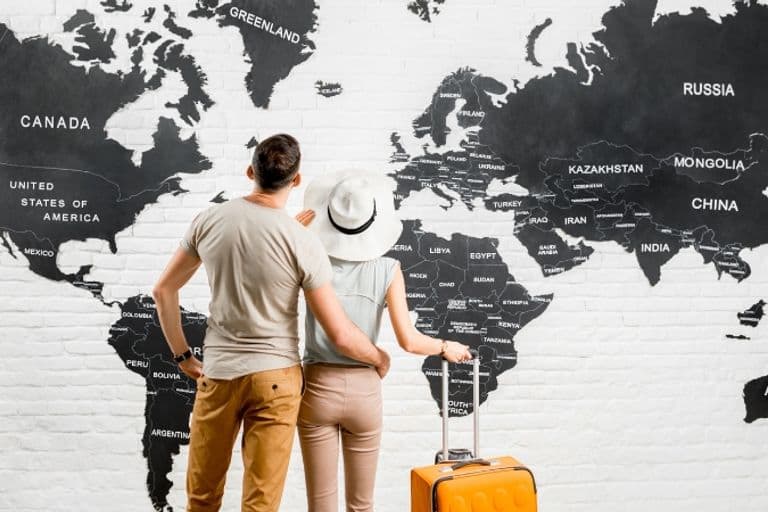 Kunden stehen vor der Weltkarte eines Reisebüros