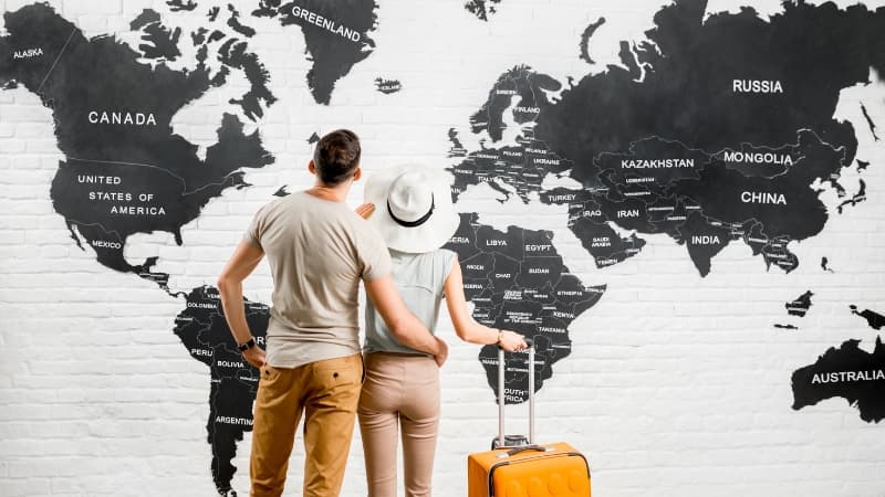 Kunden stehen vor der Weltkarte eines Reisebüros