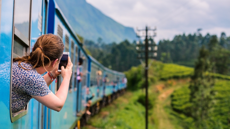 Eine junge Frau filmt aus dem Fenster eines Zugs in Sri Lanka